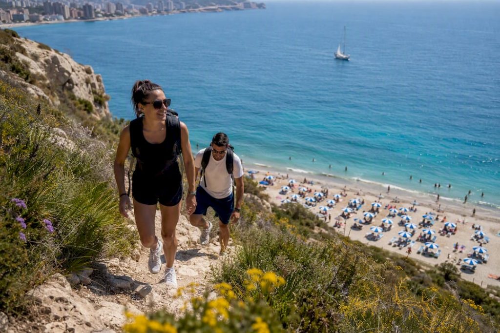 Hikers ascending Peñón de Ifach with Calpe beach below