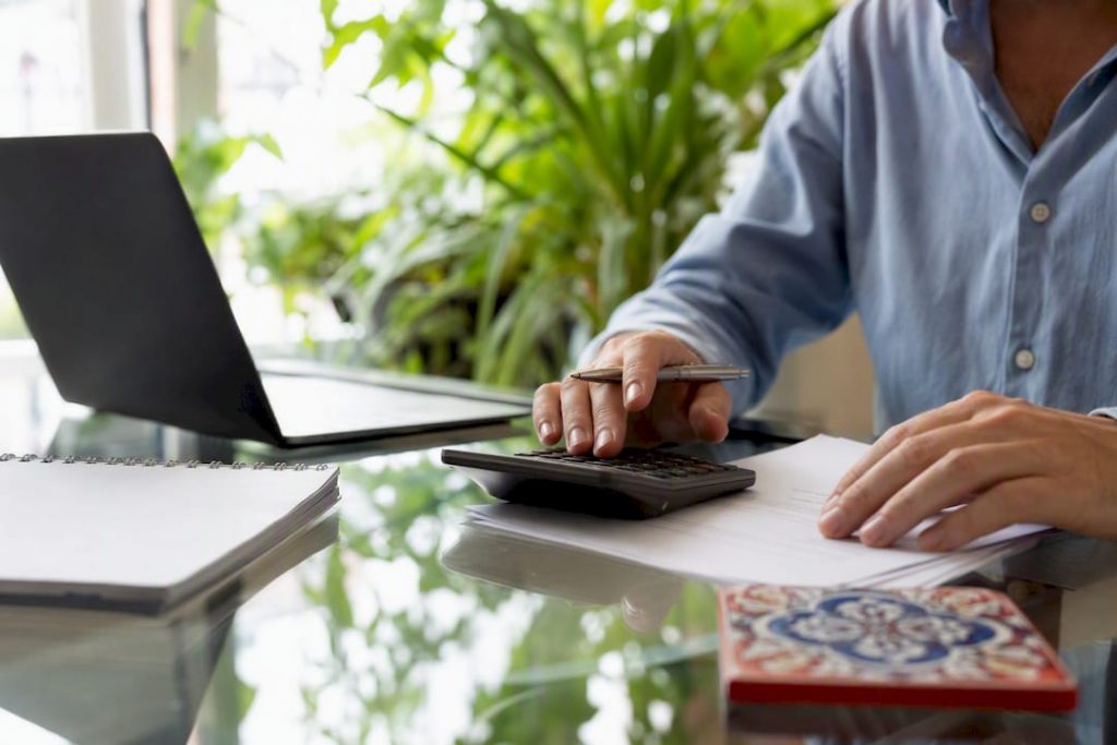 Hands calculating tax with keys and papers