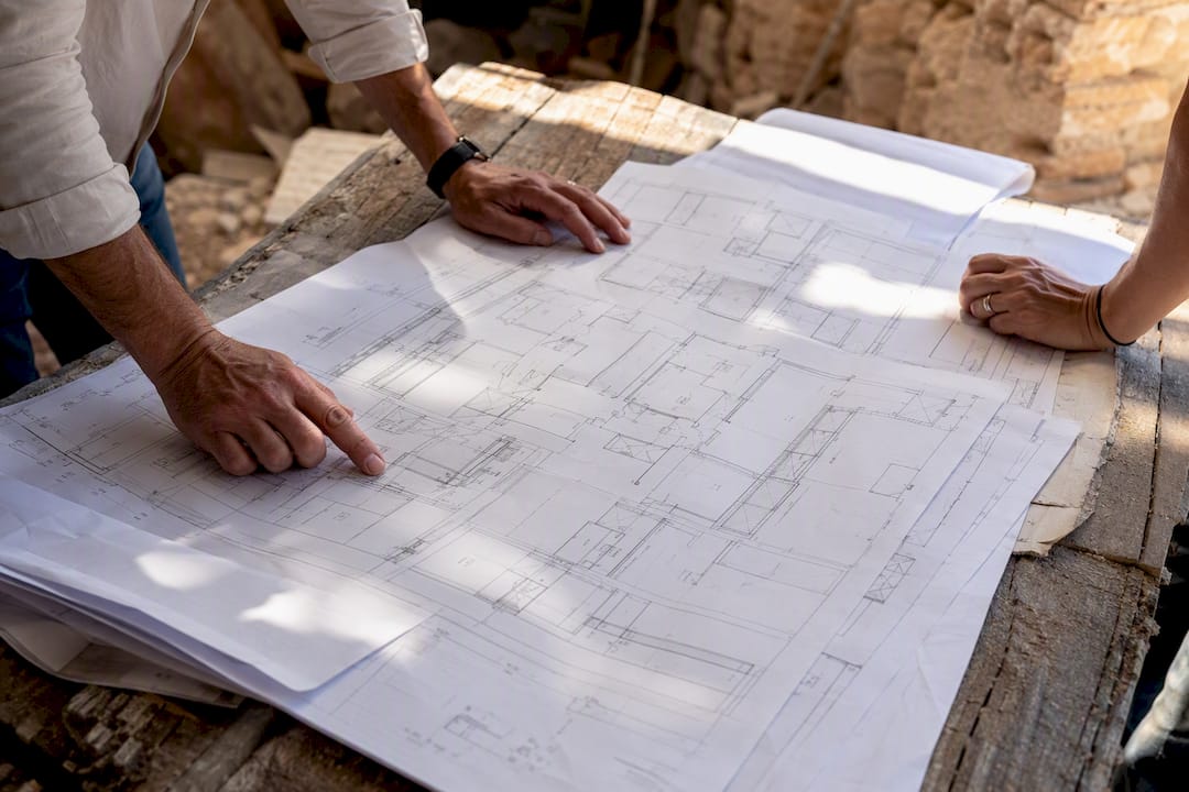 Hands examining architectural plans outdoors